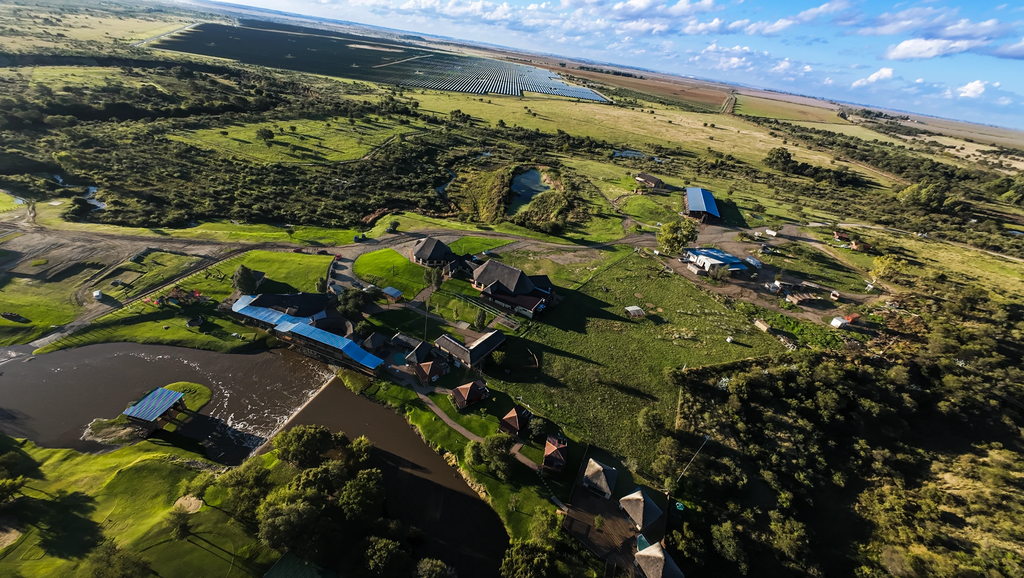 An aerial view over Goldfields Game Ranch, with the Doring River running past the thatched buildings and open Free State grassland beyond.
