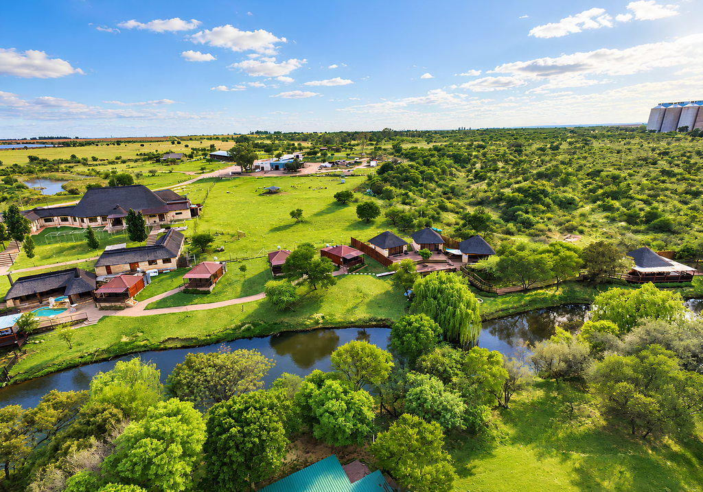 An aerial view of Goldfields Game Ranch, with the lodge, chalets and the Doring River among the trees.