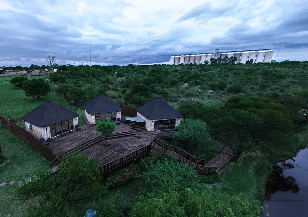 Three thatched stone units sharing a timber deck above the river at dusk.
