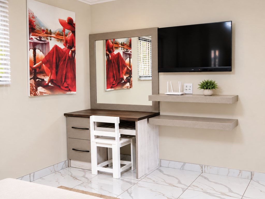 A desk and mirror beneath a wall-mounted television in a Family Room, with framed artwork alongside.