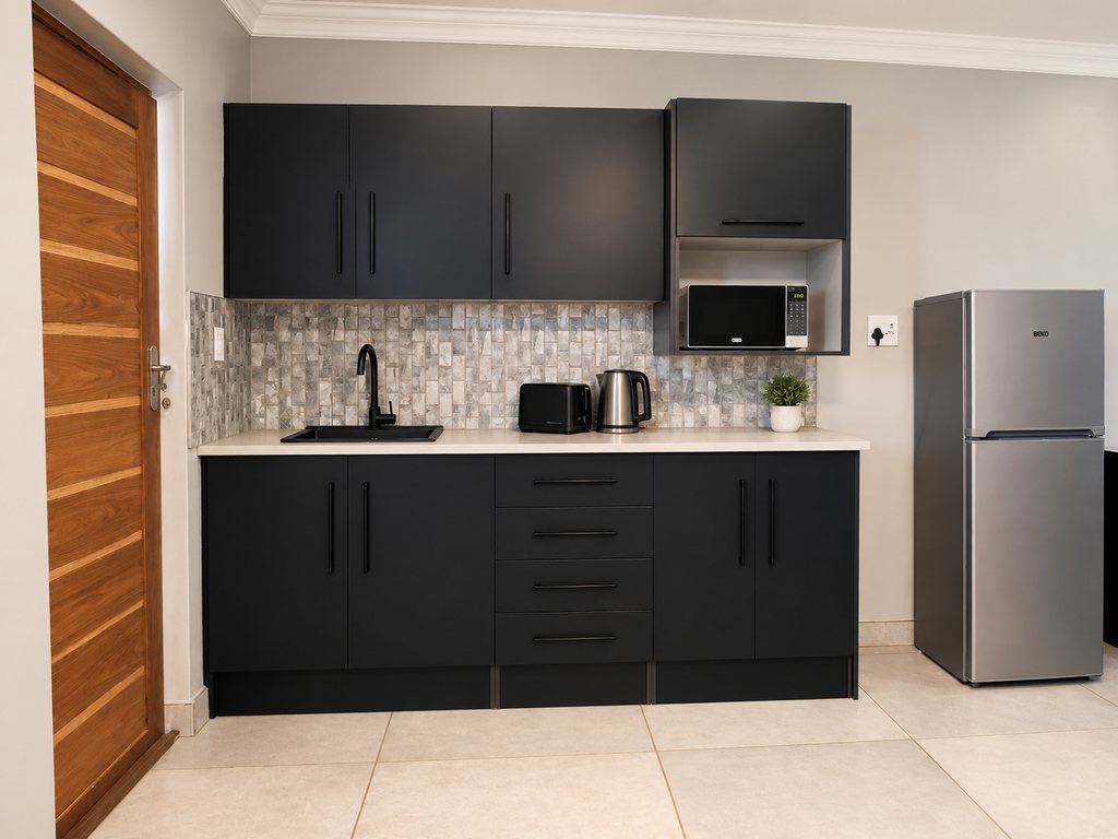 The self-catering kitchen in a Family Room, with charcoal units, a mosaic splashback, sink, kettle, toaster, microwave and fridge/freezer.