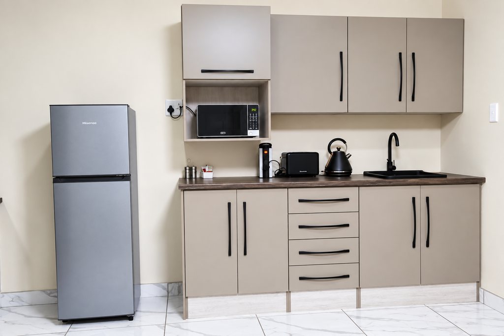 The kitchen run in a Family Room, with a fridge/freezer, microwave, kettle, toaster and a sink set in a timber worktop.