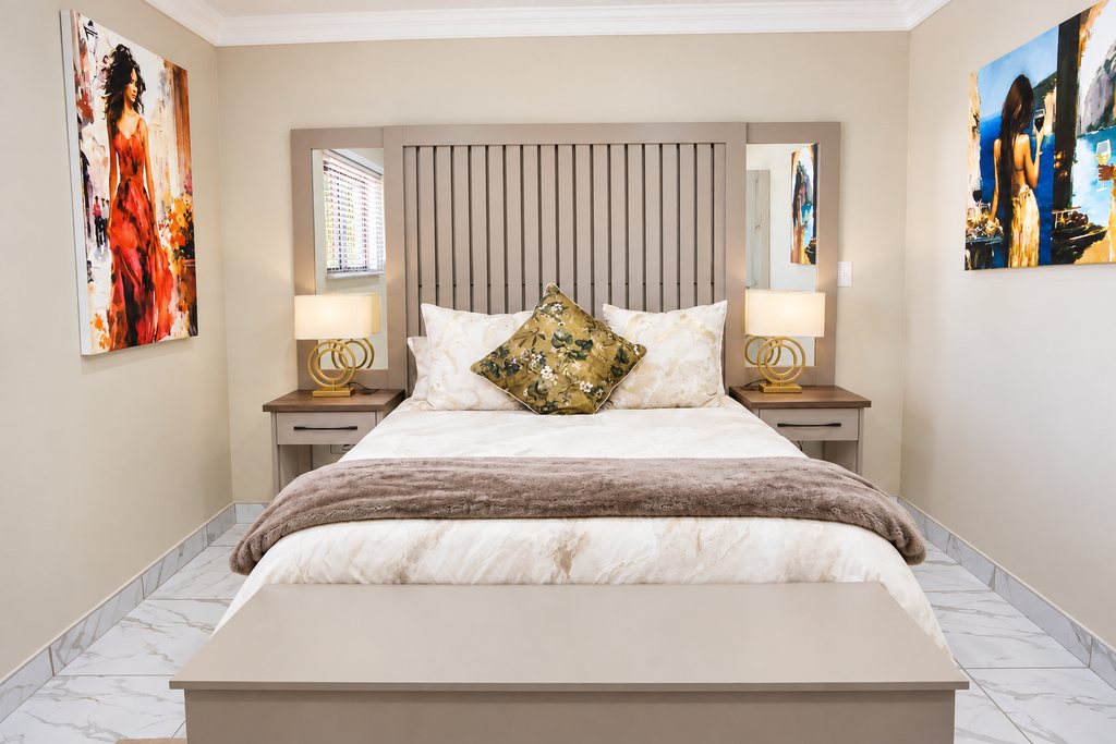 A Family Room queen bed dressed in cream linen with a floral cushion and a soft throw, between two bedside lamps.