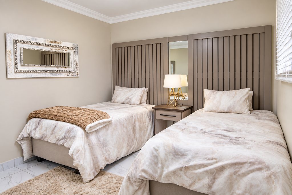 Two single beds with marbled bedding beneath a framed mirror, with a shared bedside table between them.