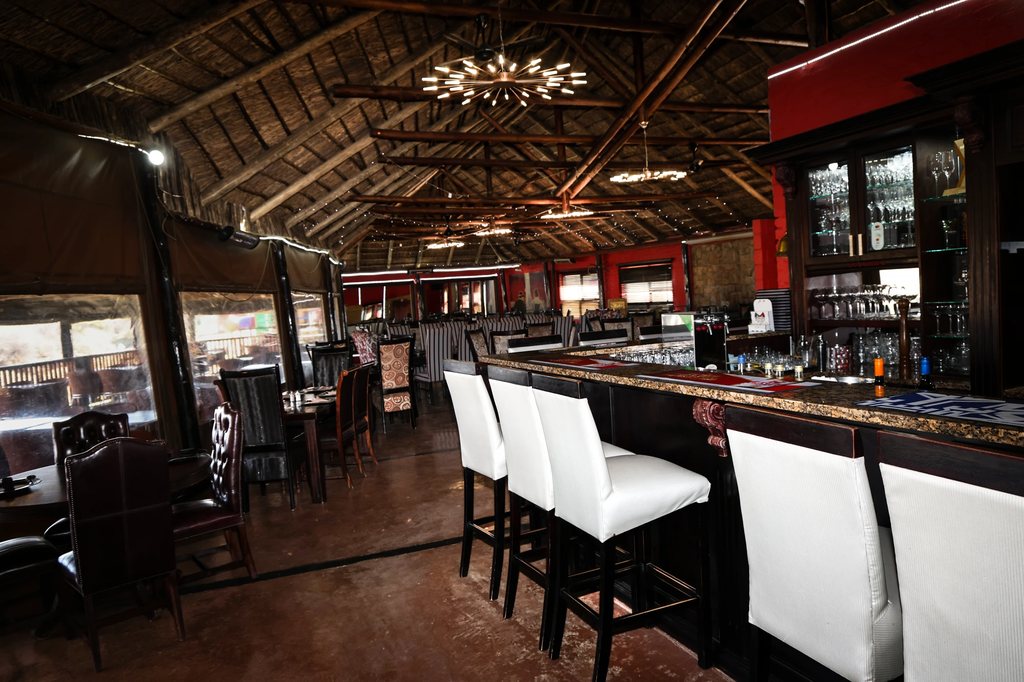 The Goldfields restaurant interior, with laid tables beside the bar under a thatched roof.