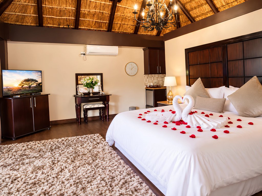 The Honeymoon Suite seen from the side, with the flat-screen television, dressing table and the dressed queen bed.