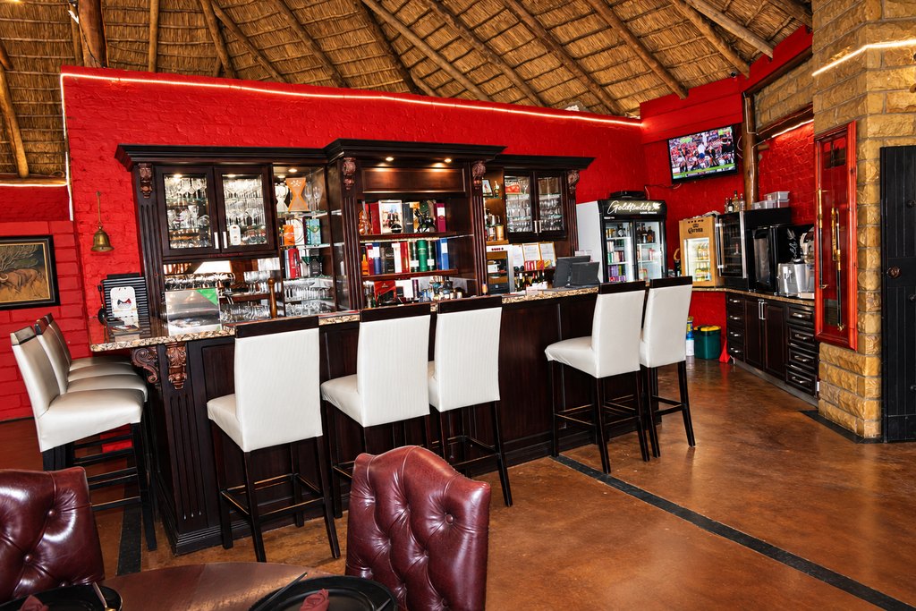The licensed bar at the Goldfields restaurant, with bar stools at the counter and glassware behind it.