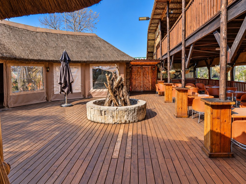 Campfire seating at the Goldfields restaurant, with a stone fire pit on the timber deck beside the tables.