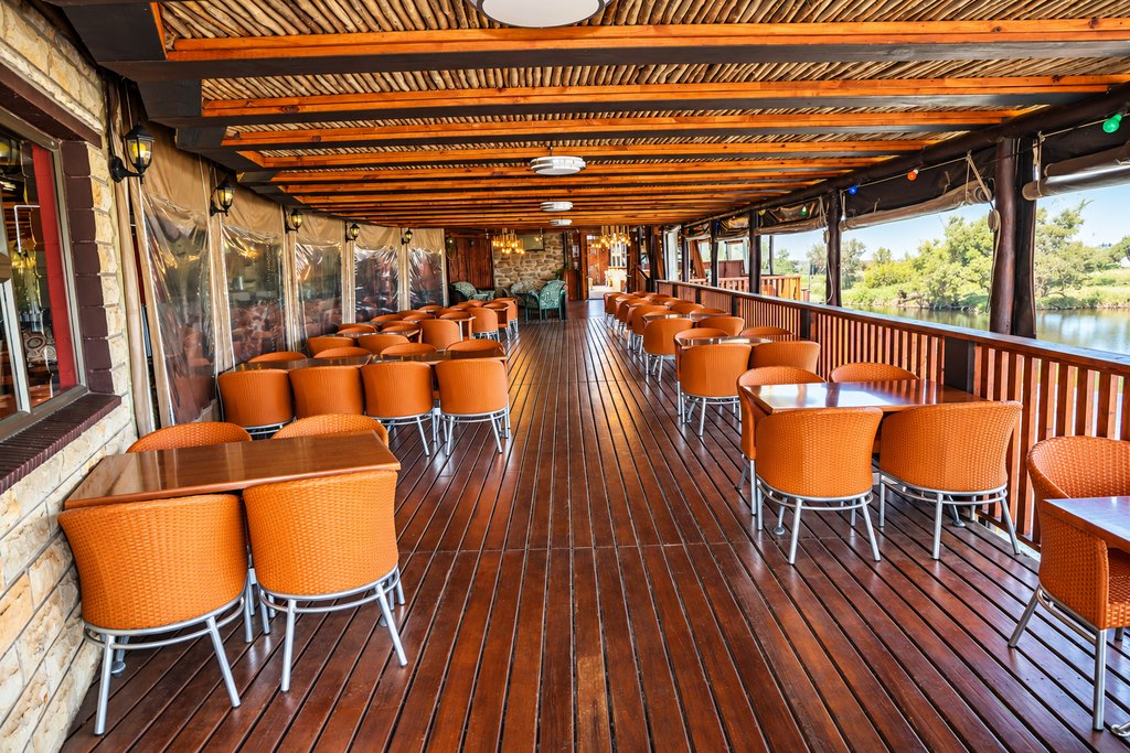 Covered outdoor seating at the Goldfields restaurant, with tables and chairs looking out over the water.