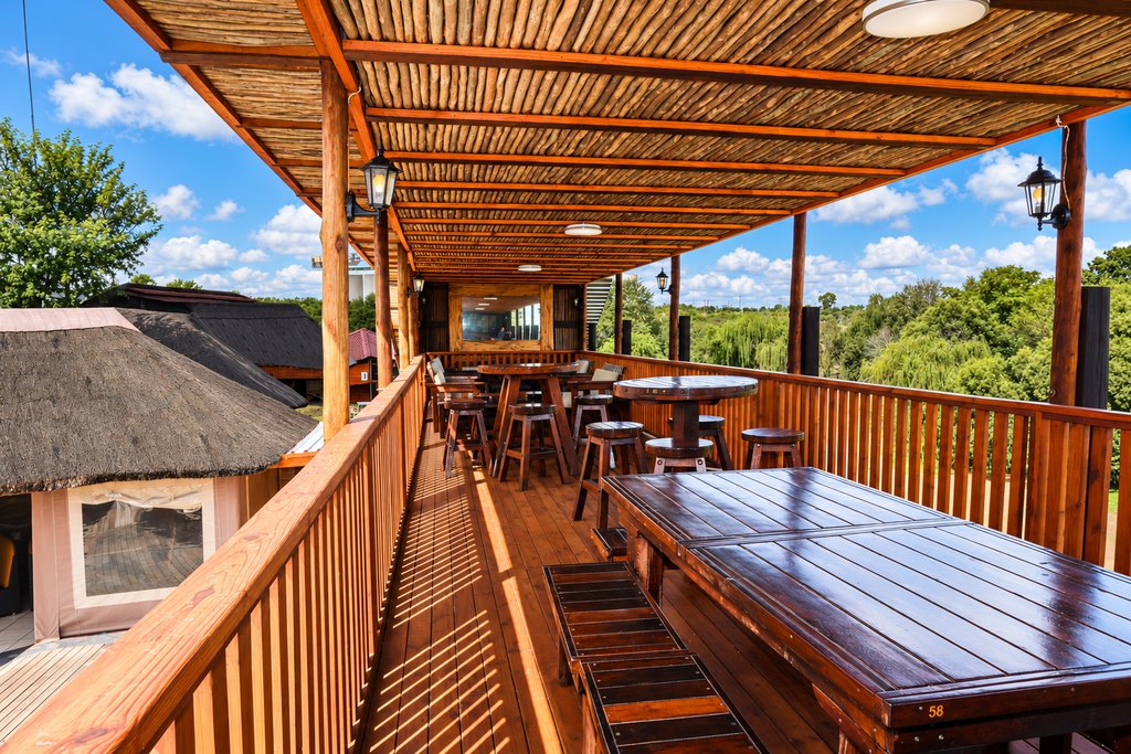 The upper deck at the Goldfields restaurant, with bar-height tables and stools under a reed roof.