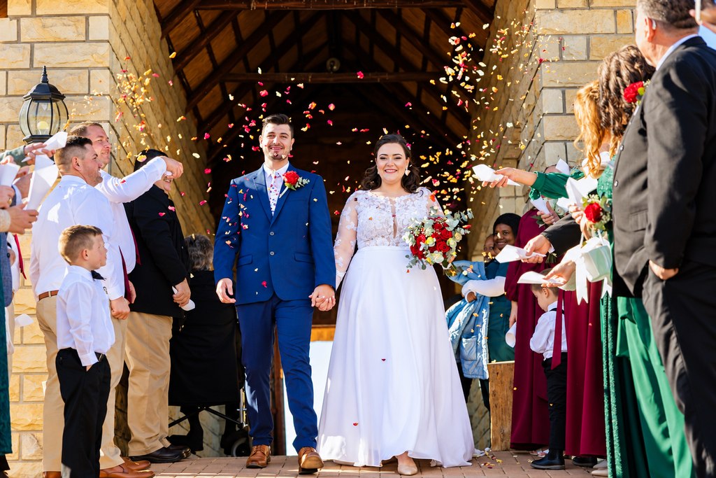 Guests showering the couple with petals as they leave through the stone passage.