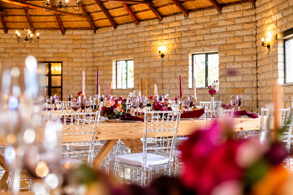 The thatched banquet hall set with long timber tables, clear chairs and taper candles.