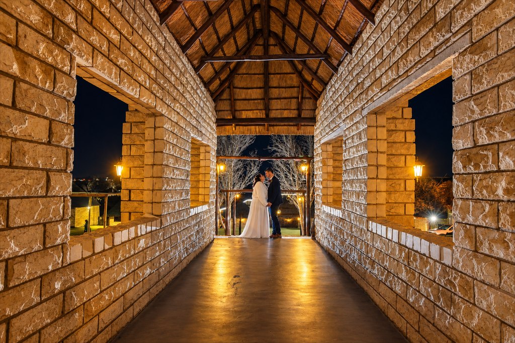 The thatched pavilion lit for an evening function, with strings of warm bulbs overhead.