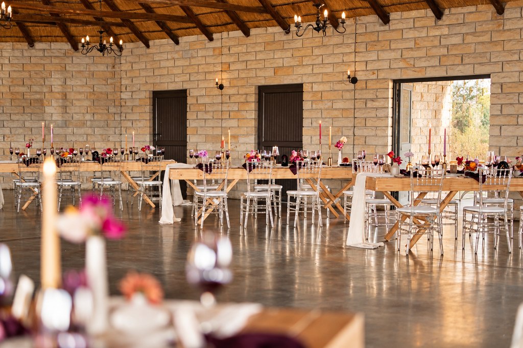 A candlelit reception table running the length of the stone hall.