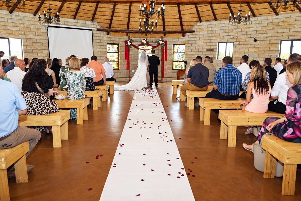 A full chapel ceremony with a petal aisle beneath the stained-glass windows.