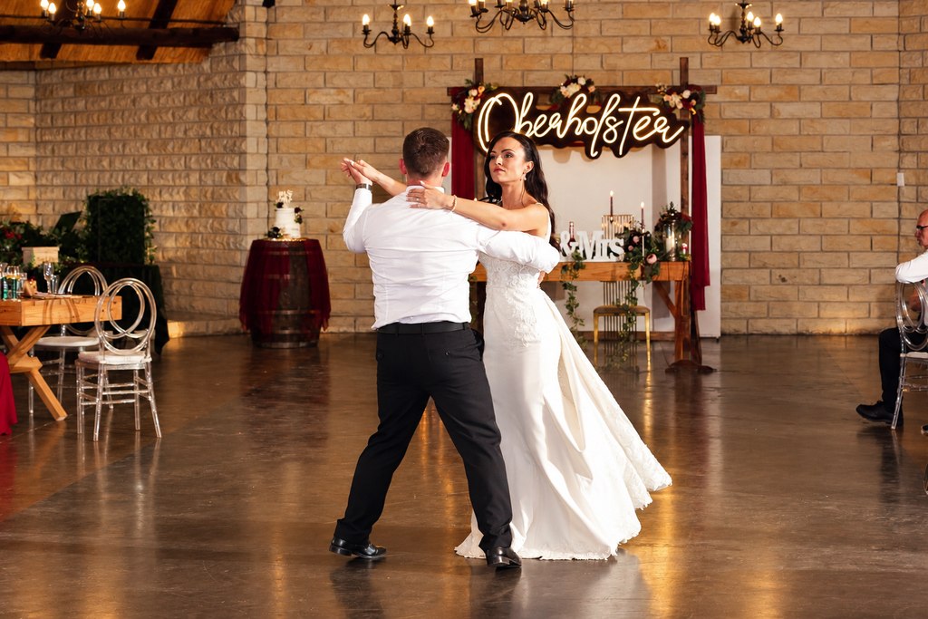 The couple dancing on the open floor of the rustic hall.