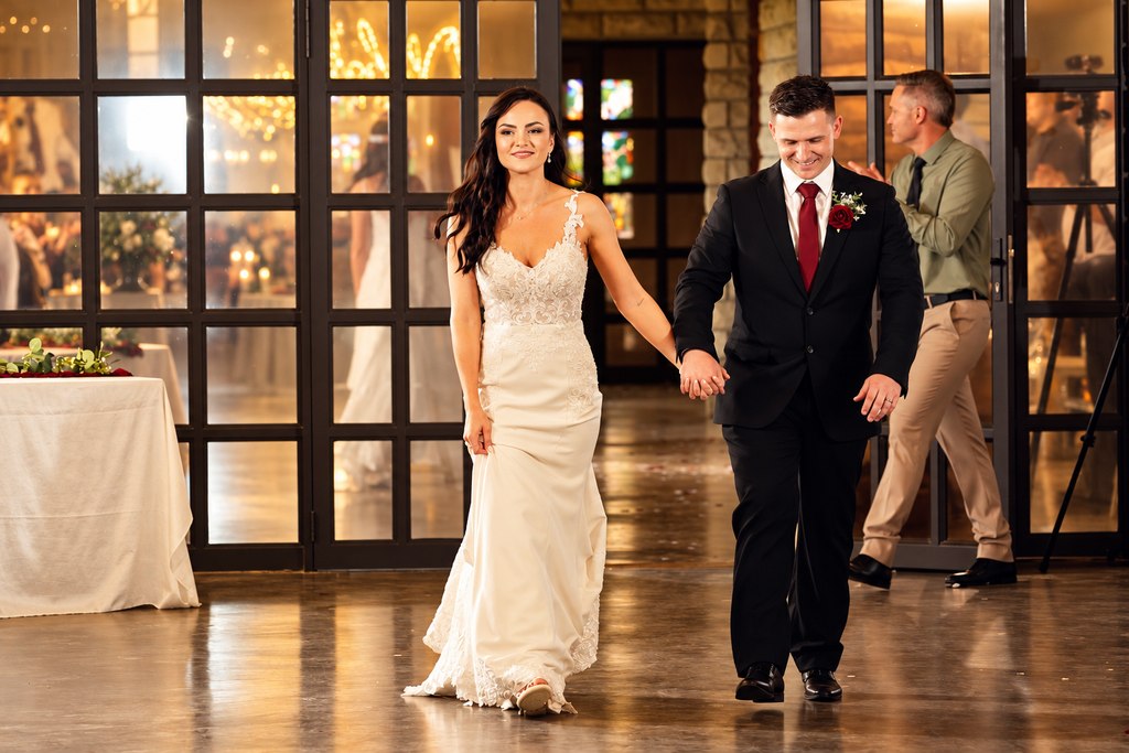 The couple entering the reception hand in hand through the glazed doors.
