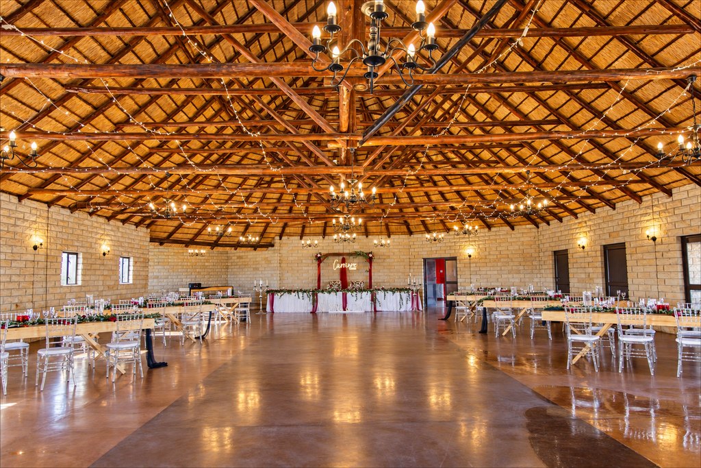 The larger Goldfields function hall under its thatched roof, set with long timber tables, clear chairs and strings of warm lights.