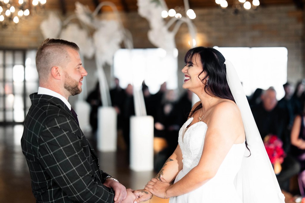 A bride and groom holding hands at the ceremony beneath pale dried installations at Goldfields Game Ranch.