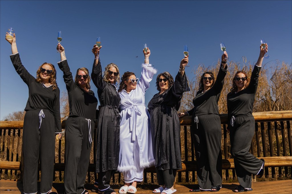 Bridesmaids in robes raising their glasses together on the timber deck at Goldfields Game Ranch.