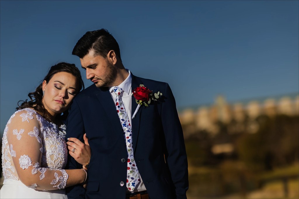 A bride and groom in a quiet embrace against deep blue sky at golden hour at Goldfields Game Ranch.