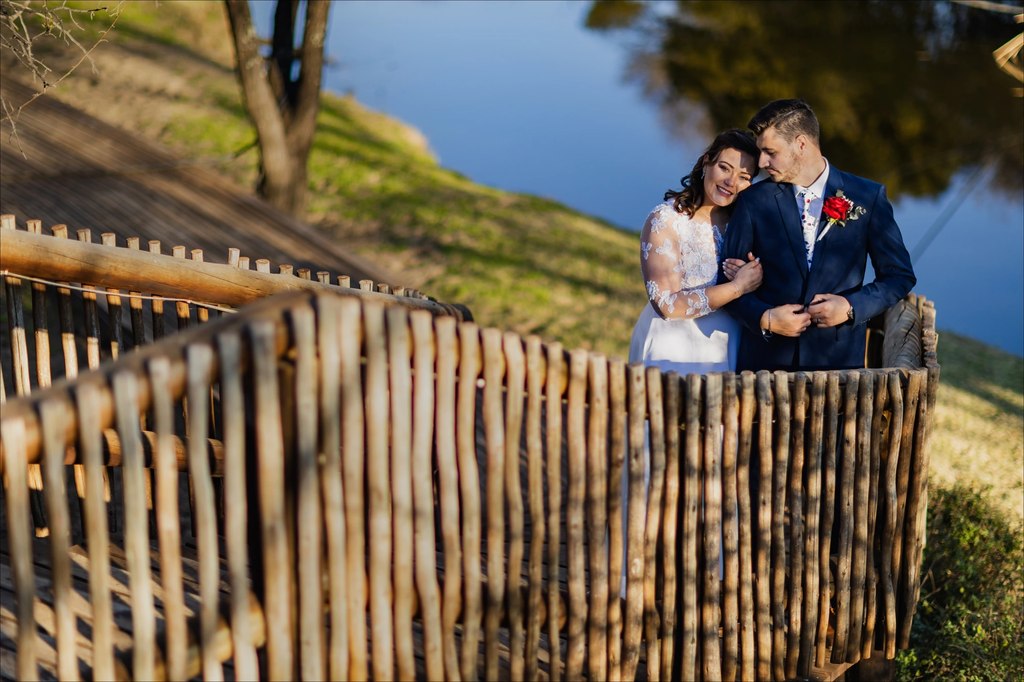 A bride and groom on the timber walkway above the dam in late afternoon light at Goldfields Game Ranch.
