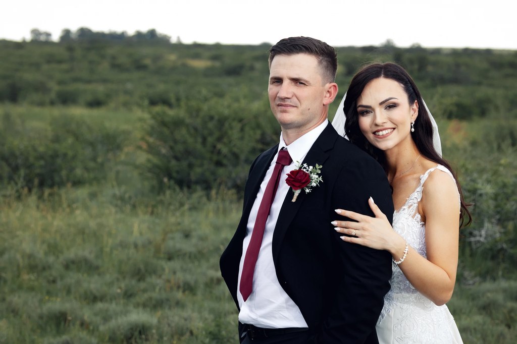 A bride and groom standing back to back in open grassland in the open Free State landscape.