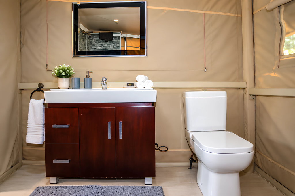 The bathroom of a wooden house, with a basin, mirror, folded towels and toilet.